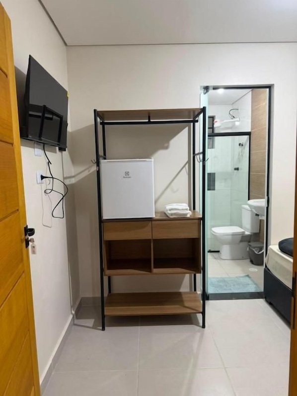 Un baño pequeño con zona de ducha, inodoro y lavamanos.