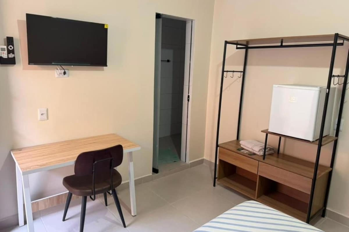 A room with a bed, a desk, a chair, a TV, and a wardrobe.