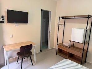 A room with a bed, a desk, a chair, a TV, and a wardrobe. - Pousada SMART AIRPORT 10min (Guarulhos)