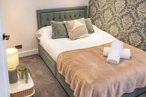 A neatly made bed with a green headboard, white linens, and a brown throw blanket. - 3-bed Terrace House in Porth, Sleeps 6 (Porth)