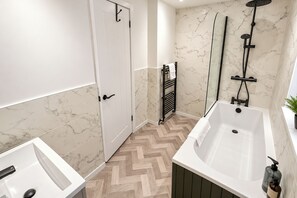 A modern bathroom with a freestanding bathtub, a shower, and a white door. - 3-bed Terrace House in Porth, Sleeps 6 (Porth)