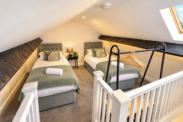 A bedroom with two beds, a hanging chair, a small table with a lamp, and a ceiling light. - 3-bed Terrace House in Porth, Sleeps 6 (Porth)