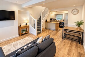 A modern living space with a staircase, a kitchen, and a dining area. - 3-bed Terrace House in Porth, Sleeps 6 (Porth)