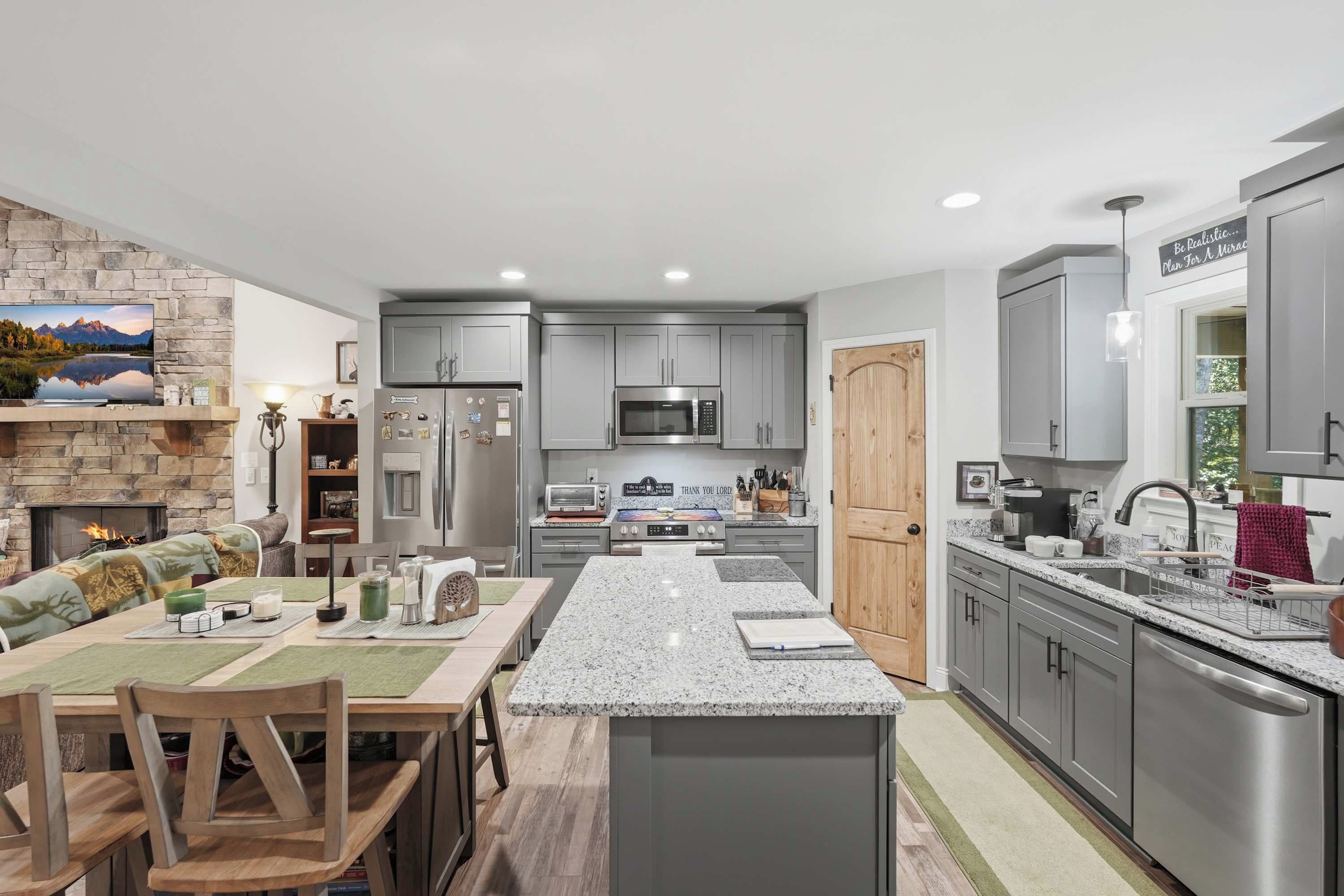 A modern kitchen with granite countertops, stainless steel appliances, and grey cabinetry.