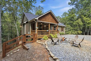 A cabin with a porch, a fire pit, and outdoor seating.