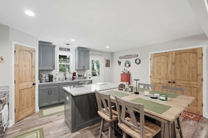 Una cocina moderna con armarios grises, una isla central y un comedor con sillas de madera.