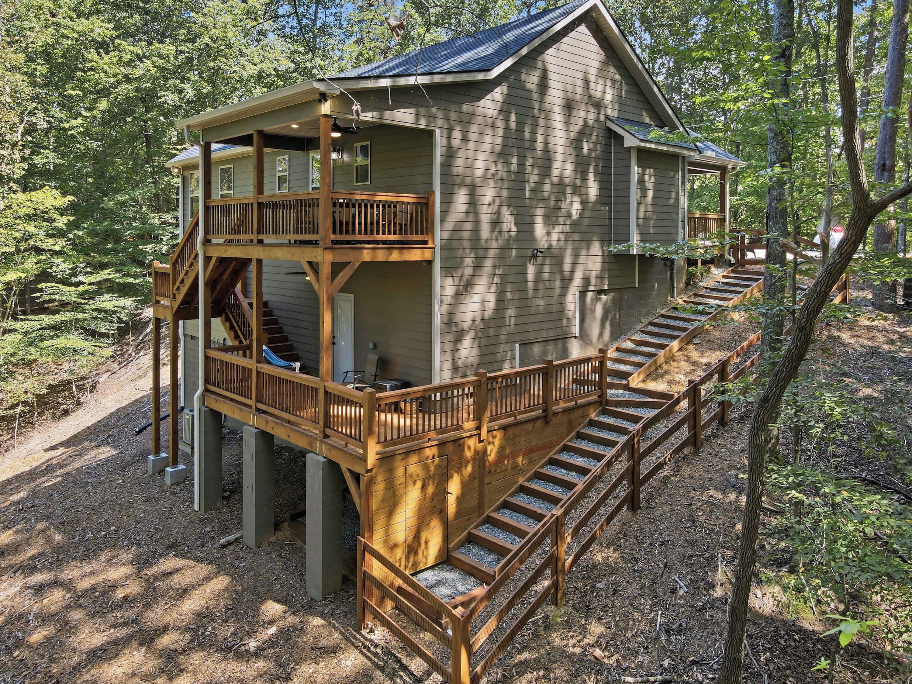 A two-story wooden cabin with a balcony, surrounded by trees.