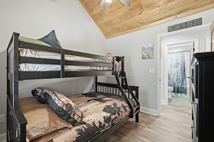 Una cama litera con una escalera, una puerta con un letrero que dice 'Bienvenido al Zoo' y un cuadro en la pared.
