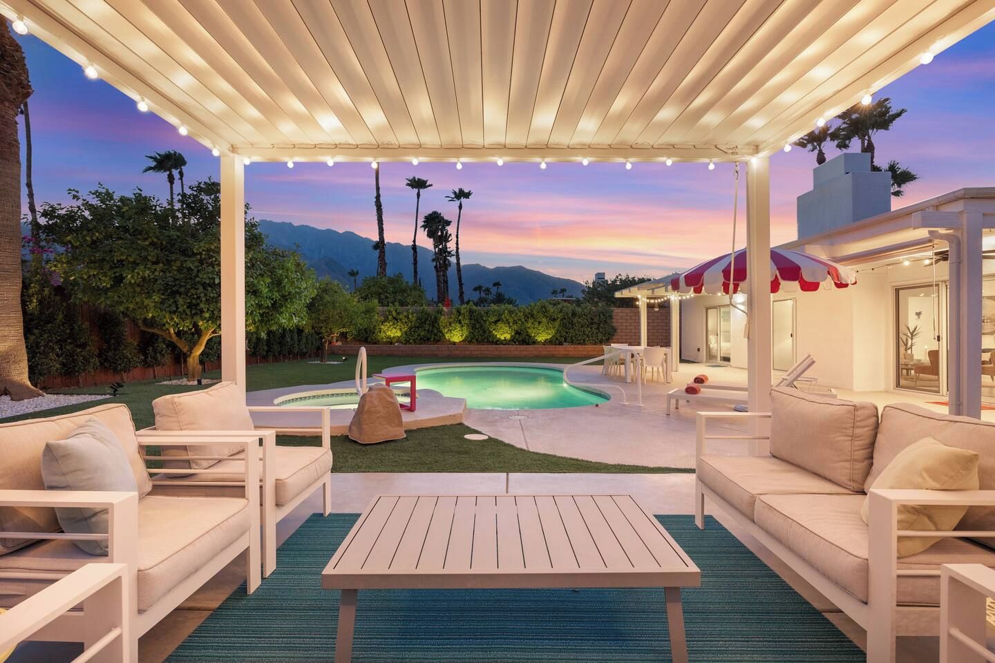 Un espacio al aire libre techado con piscina, asientos y vistas a montañas.