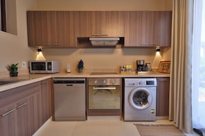 Une cuisine compacte dotée de meubles en bois, d’un four à micro-ondes, d’un lave-vaisselle et d’une machine à laver.