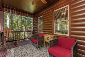 Ein Blockhaus-Interieur mit Veranda, Korbmöbeln, einer Hängematte und einer Holzkiste.