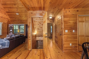 A wooden cabin interior with a sofa, a hallway, and a door.