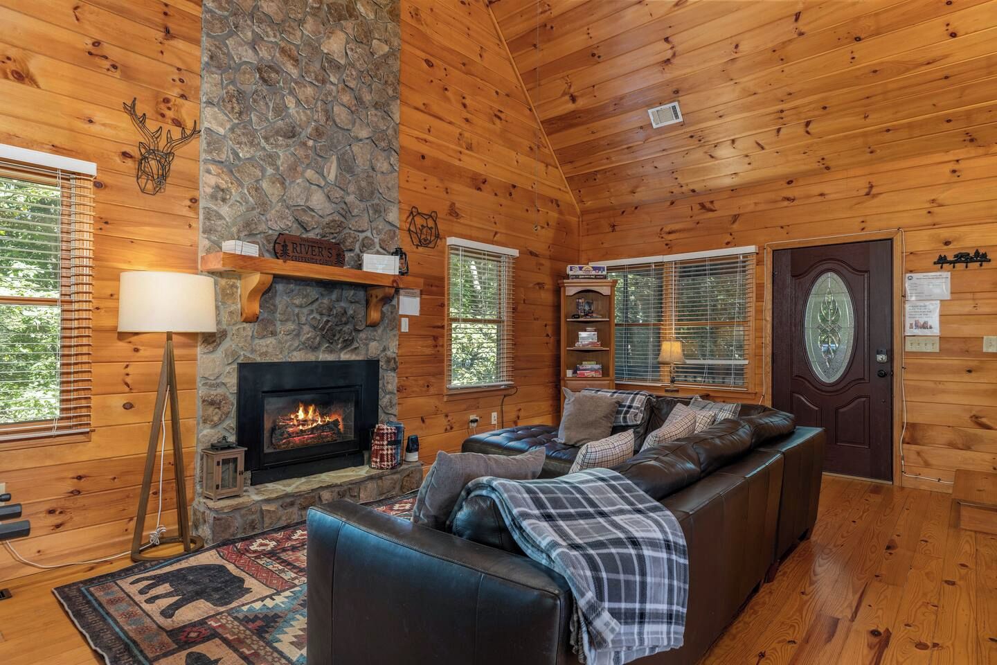 L'intérieur d'une cabane en rondins, avec une cheminée en pierre, un canapé et une lampe.