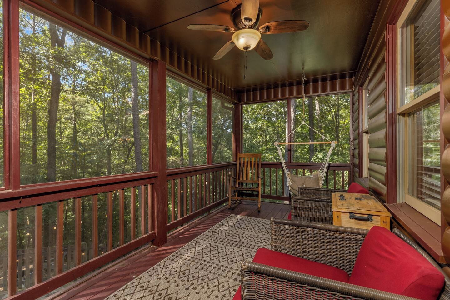 Eine Hütte mit Veranda, Deckenventilator und Blick ins Waldgebiet.