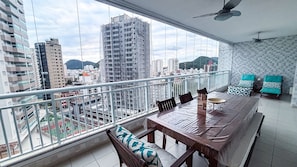 Ein Balkon mit Esstisch, Stühlen und Blick auf eine Stadtlandschaft mit Gebäuden und Bergen.