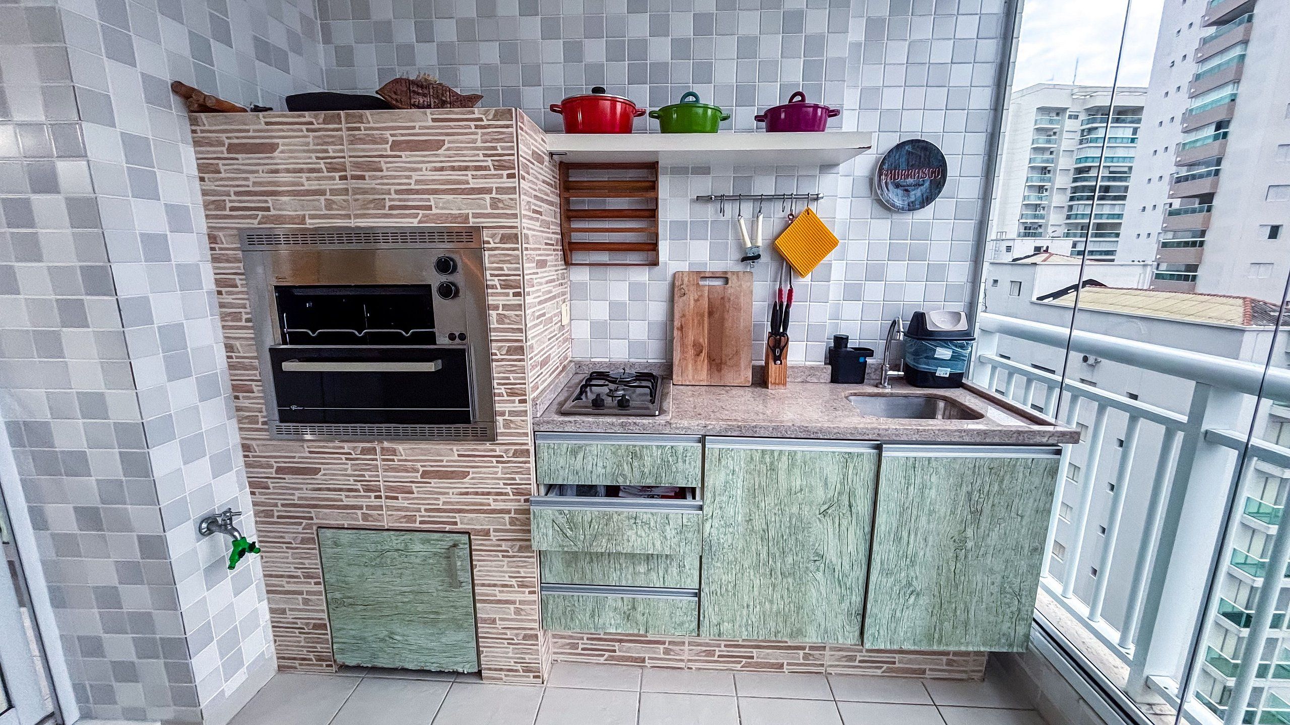Cocina compacta con horno integrado, estufa a gas y un lavamanos pequeño.