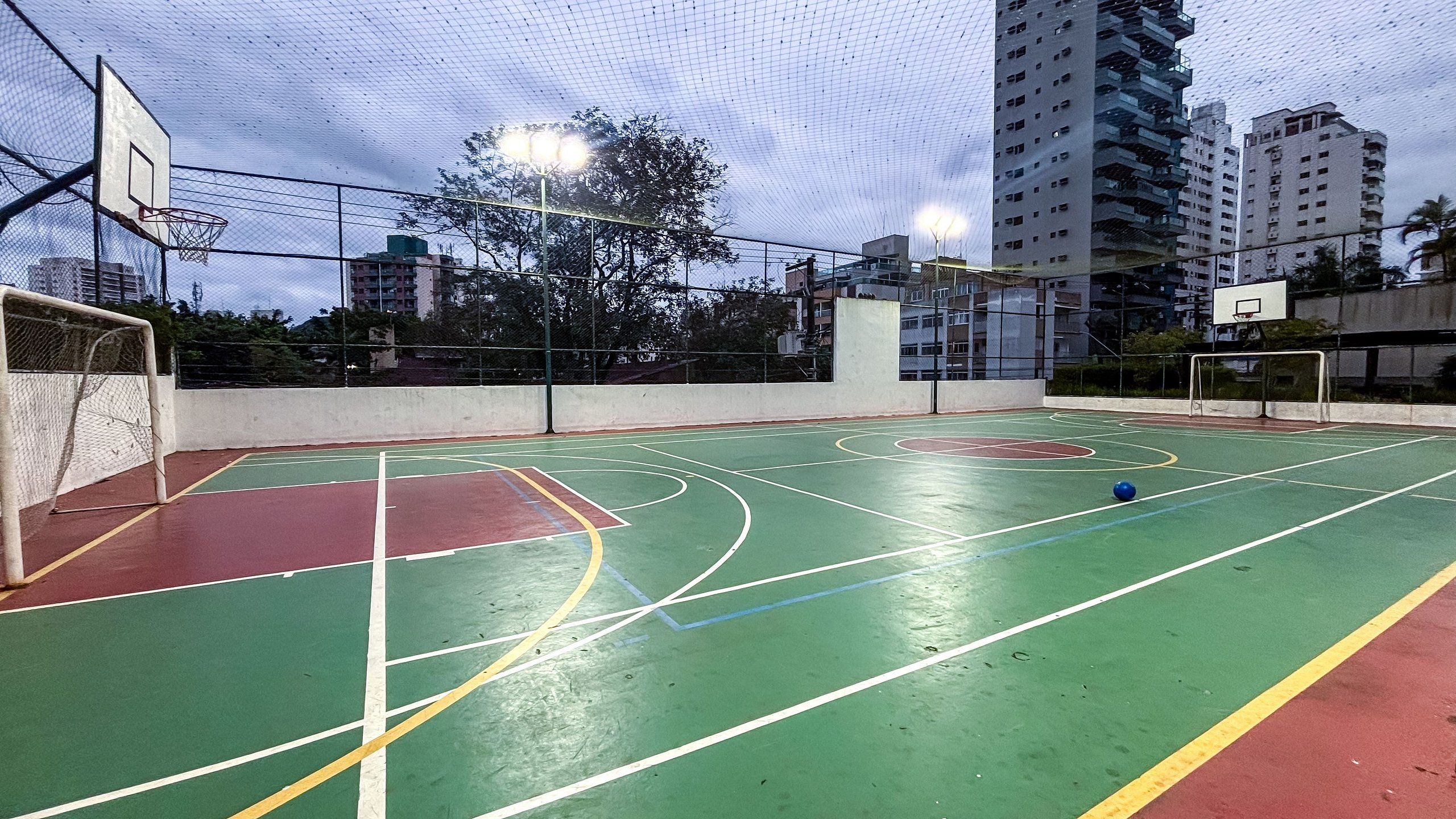 An outdoor basketball court with a net, goalpost, and court lines.