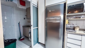 Eine Küche mit einem Edelstahl-Kühlschrank, einer Waschmaschine und einem Besen.