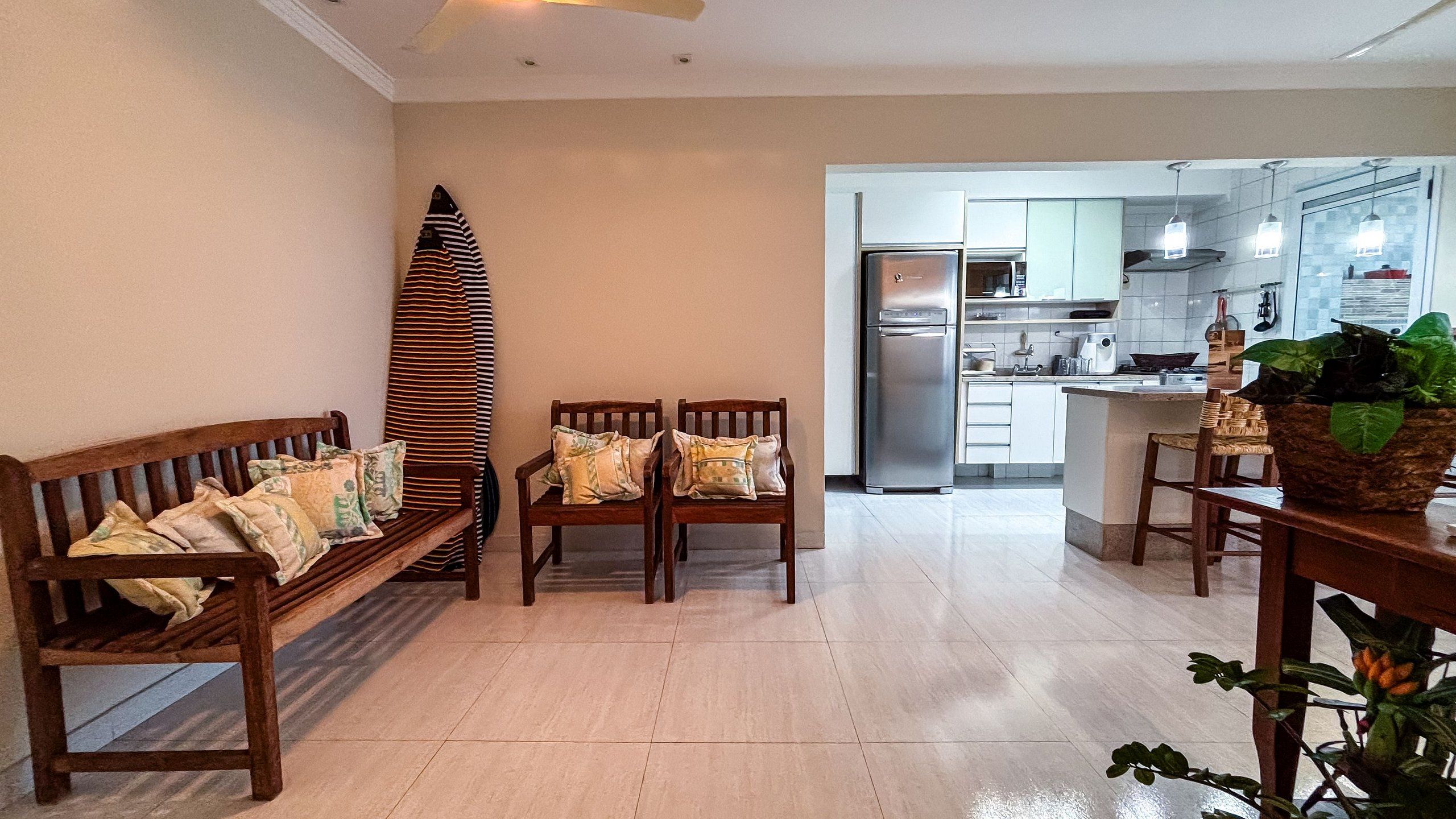 Cocina moderna con refrigerador, microondas y estufa. Hay un banco de madera con cojines y una mesa de comedor con sillas.