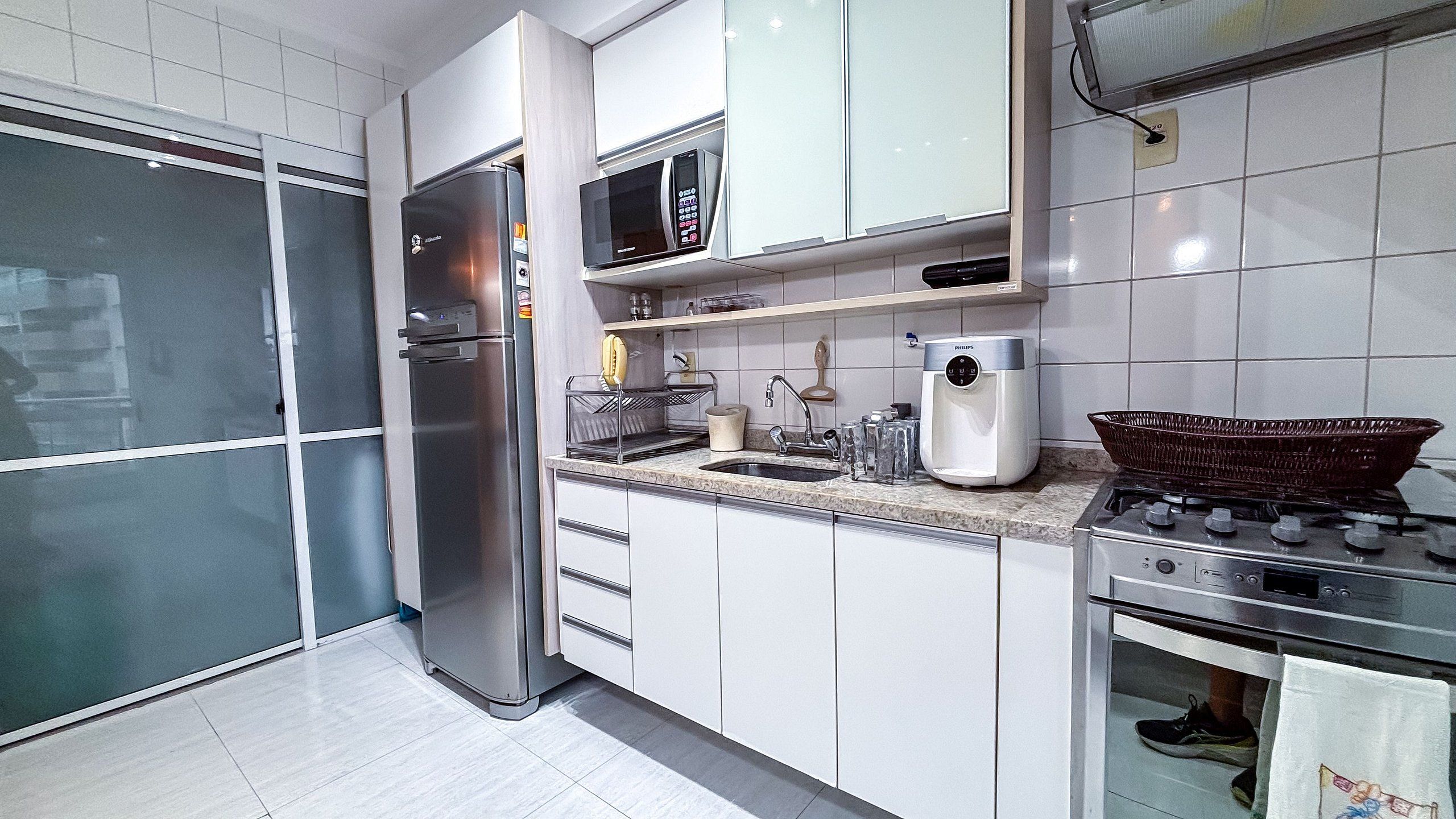 Una cocina moderna con electrodomésticos de acero inoxidable, armarios blancos y una estufa a gas.