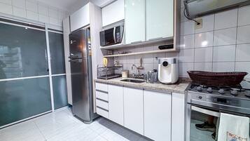 Una cocina moderna con electrodomésticos de acero inoxidable, armarios blancos y una estufa a gas.
