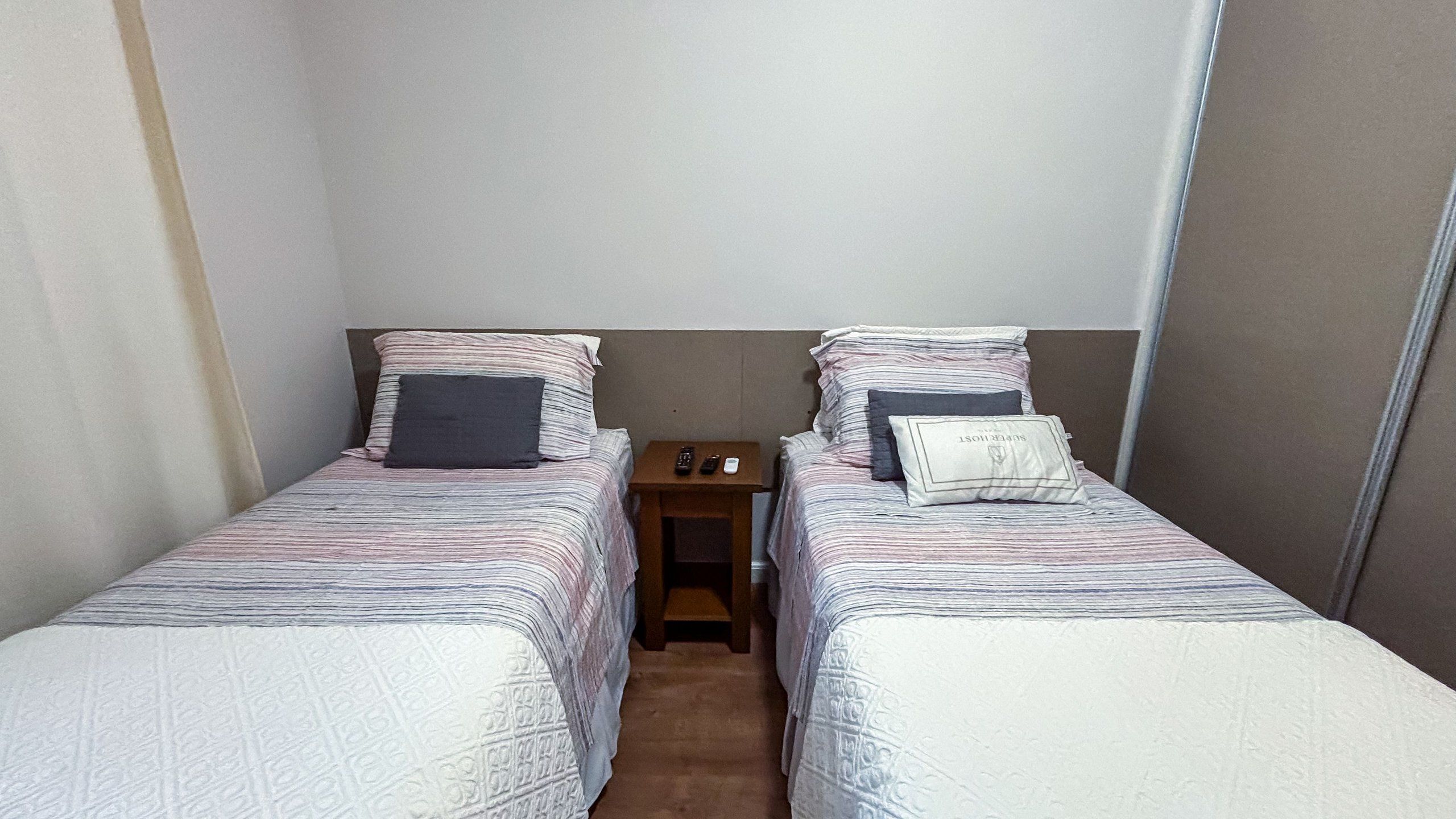 Habitación doble con dos camas individuales, cada una con una almohada y una manta.