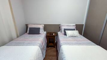 Habitación doble con dos camas individuales, cada una con una almohada y una manta.