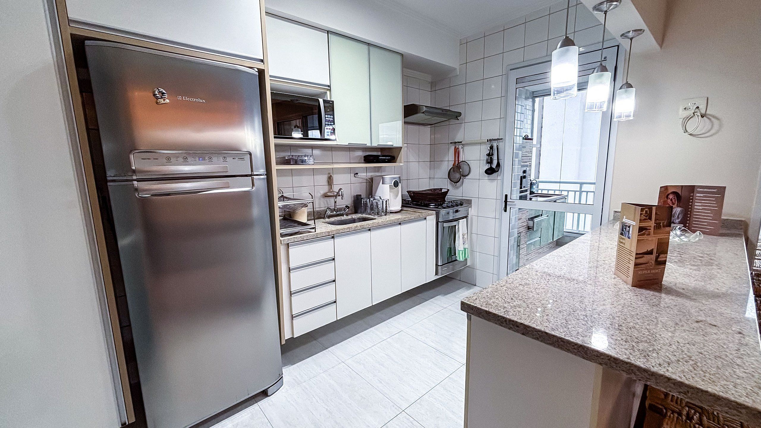 Una cocina moderna con electrodomésticos de acero inoxidable, armarios blancos y una encimera de granito.