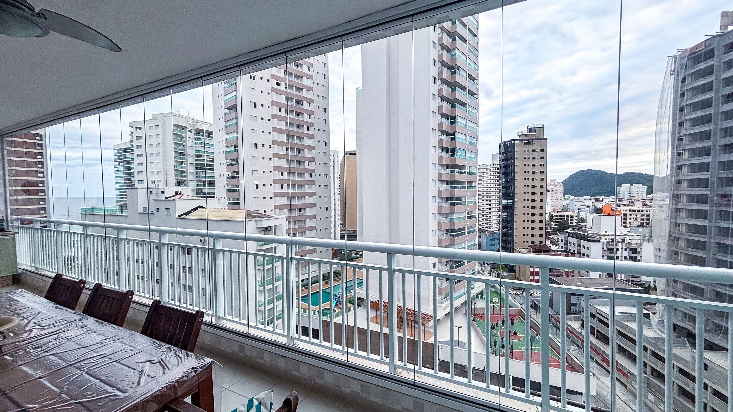 Een balkon met uitzicht op hoge gebouwen en een sportveld.