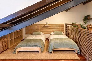 A bedroom with two beds, wooden slats on the walls, and a sloped ceiling.