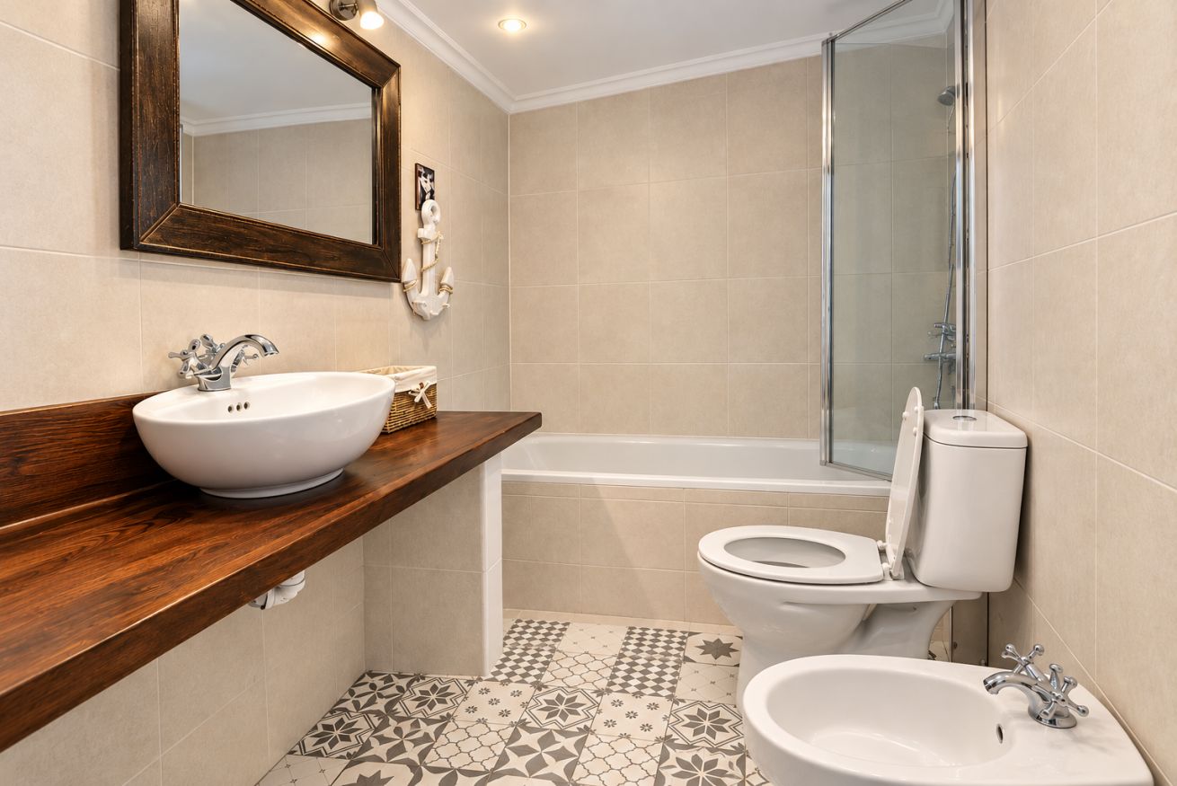 Un baño con tocador de madera, un lavabo blanco, una bañera y un inodoro.