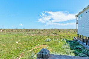 Ein weißes Gebäude mit einer Terrasse mit Blick auf ein grünes Feld und einen klaren Himmel.