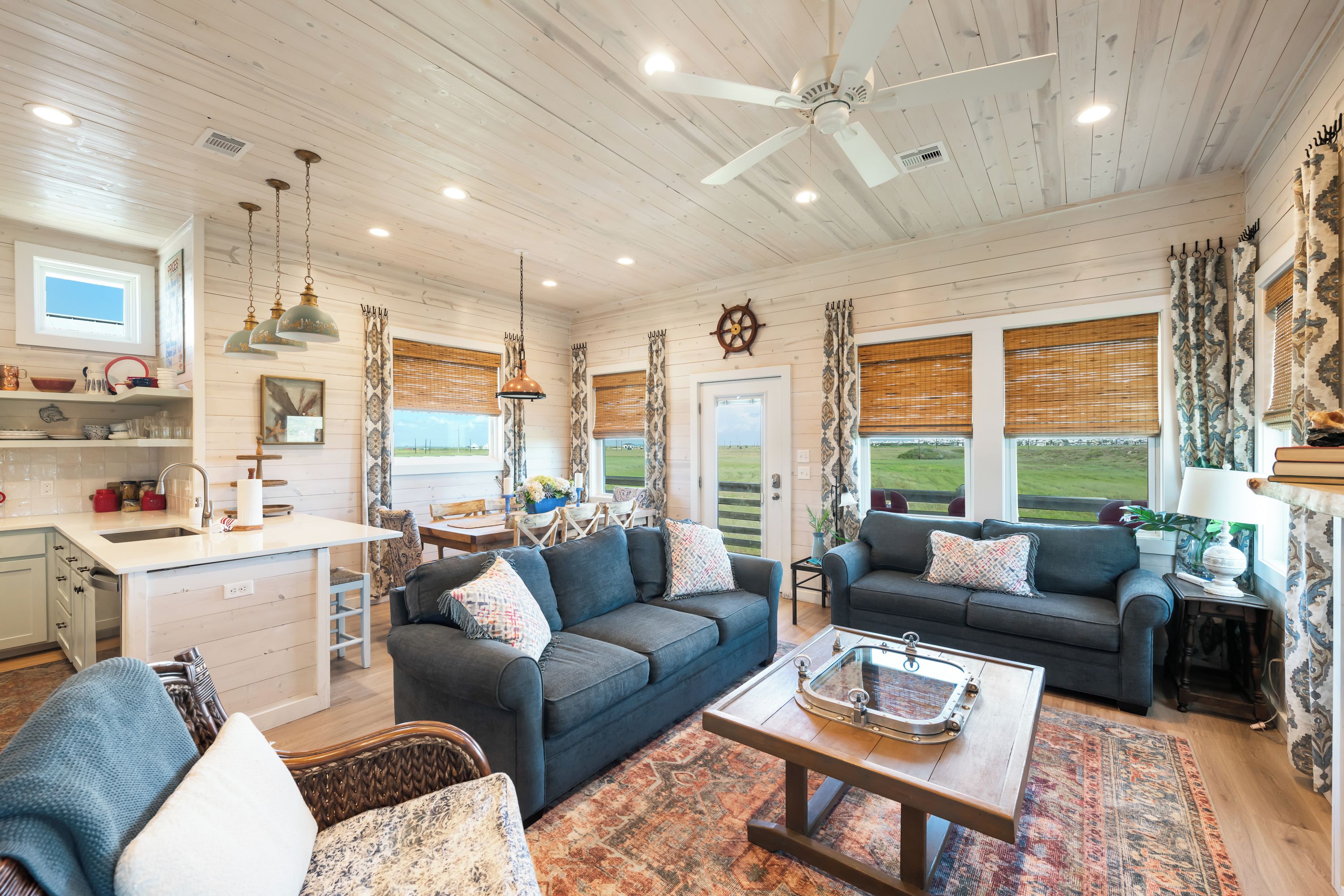 A spacious living area with a sofa, a coffee table, and a view of the outdoors through large windows.