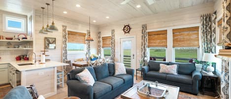 A spacious living area with a sofa, a coffee table, and a view of the outdoors through large windows.
