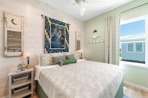 Un dormitorio con una cama, una mesita de noche, una lámpara y un ventanal con cortinas.