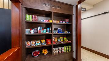 A pantry with shelves stocked with snacks, beverages, and fruits.