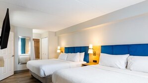 Ein Hotelzimmer mit zwei Betten, Holzboden und einem blauen Kopfteil.