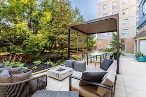 An outdoor patio with seating, a fire pit, and a pergola.