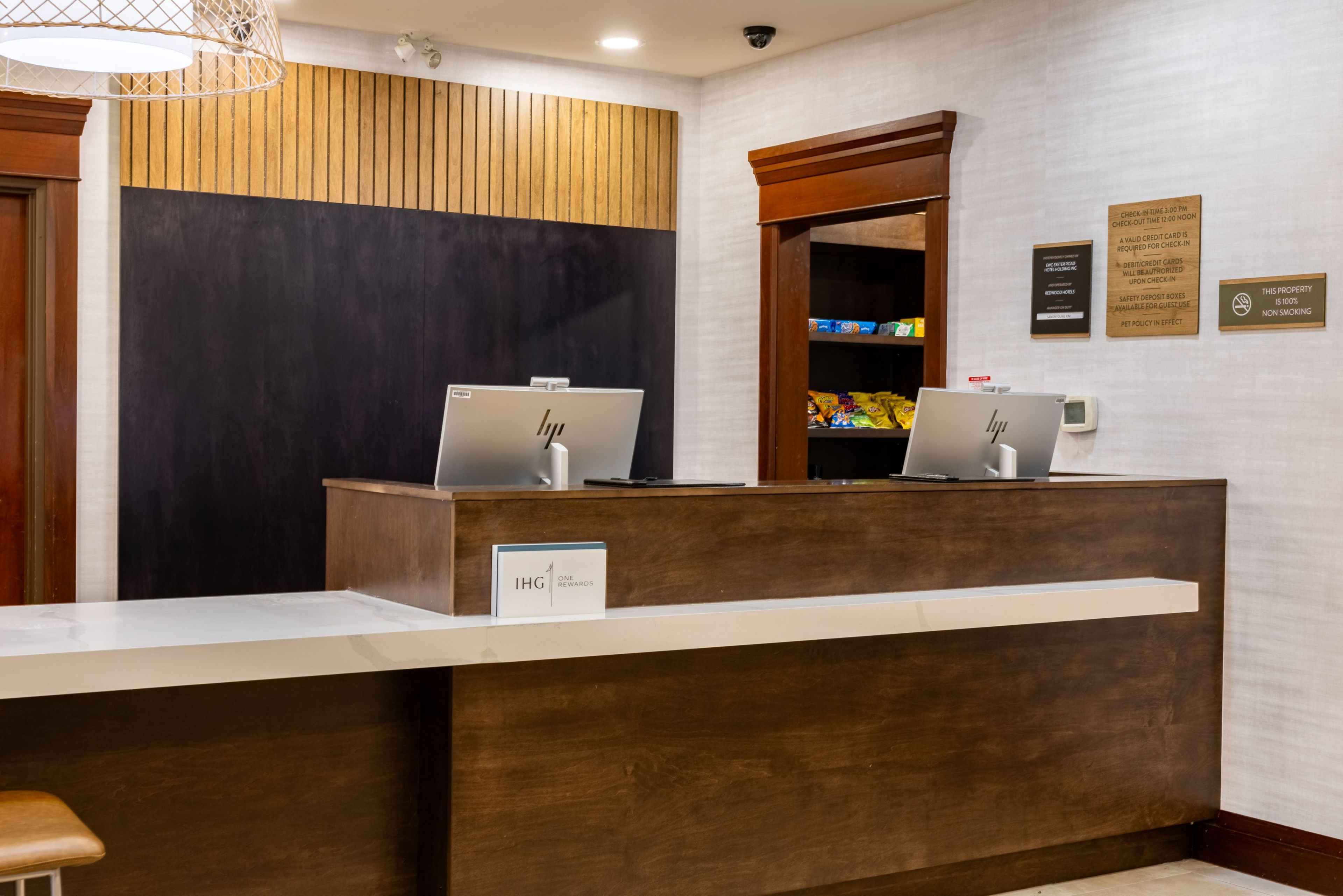 Un comptoir d’accueil avec deux ordinateurs portables HP, une enseigne indiquant « IHG One Awards », et une caméra de surveillance au-dessus.