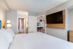 Habitación de hotel con cama, televisión montada en la pared, escritorio y zona de ducha.