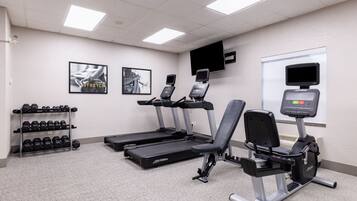 Centro de fitness com esteiras, elípticos e suporte para halteres.