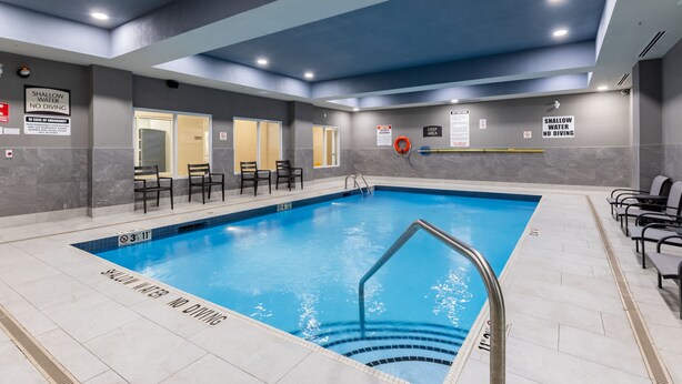 An indoor swimming pool with clear safety signage, a diving board, and seating areas. - King Studio w/ Jetted Tub | Pool + Hot Breakfast (London)