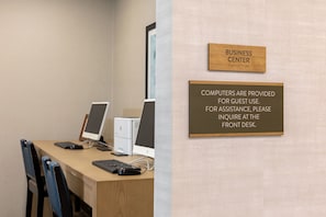Um centro de negócios com mesa, computadores e cadeiras.