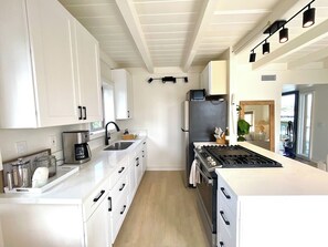 Una cocina moderna con armarios blancos, una isla central, una estufa y un refrigerador.