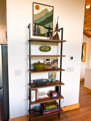 Ein hölzernes Bücherregal mit Büchern, einem grünen Topf und einem Catan-Brettspiel.