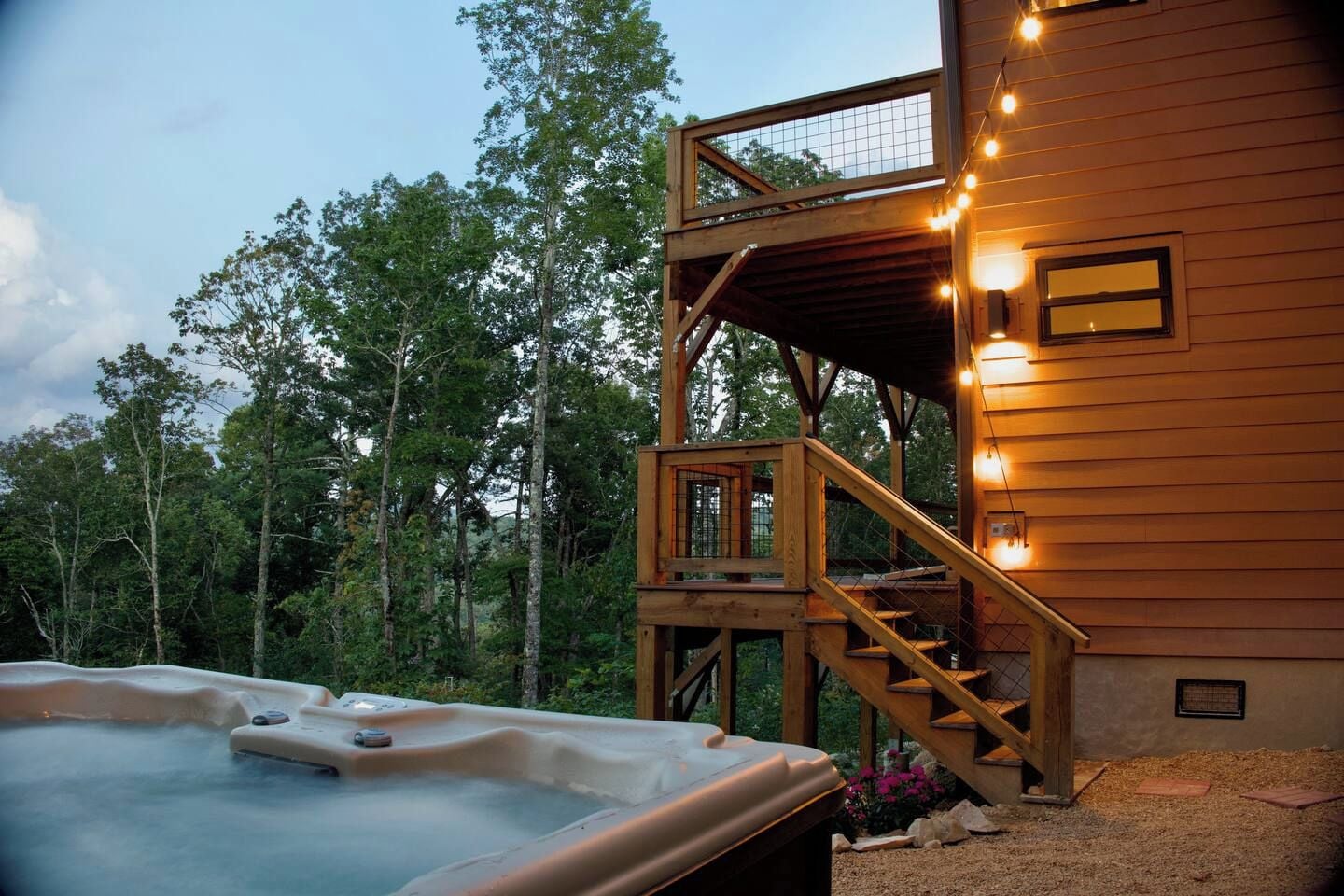 Eine Holzhütte mit Whirlpool, einer Terrasse und einer Treppe zu einer oberen Ebene.