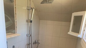 Ein kleines Badezimmer mit Toilette, Waschbecken, Dusche und einem Fenster.
