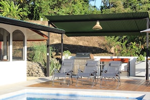 A poolside area with lounge chairs, a barbecue grill, and a pergola. - Casa Mirador, a jungle retreat near the beach (Baru)