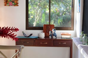 A desk with a window, a chair, and various decorative items including a plant, figurines, and books. - Casa Mirador, a jungle retreat near the beach (Baru)