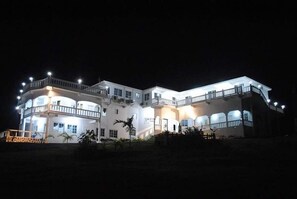 A multi-story building with balconies and a well-lit facade at night. - Da Villa Juanita  (Hordley)